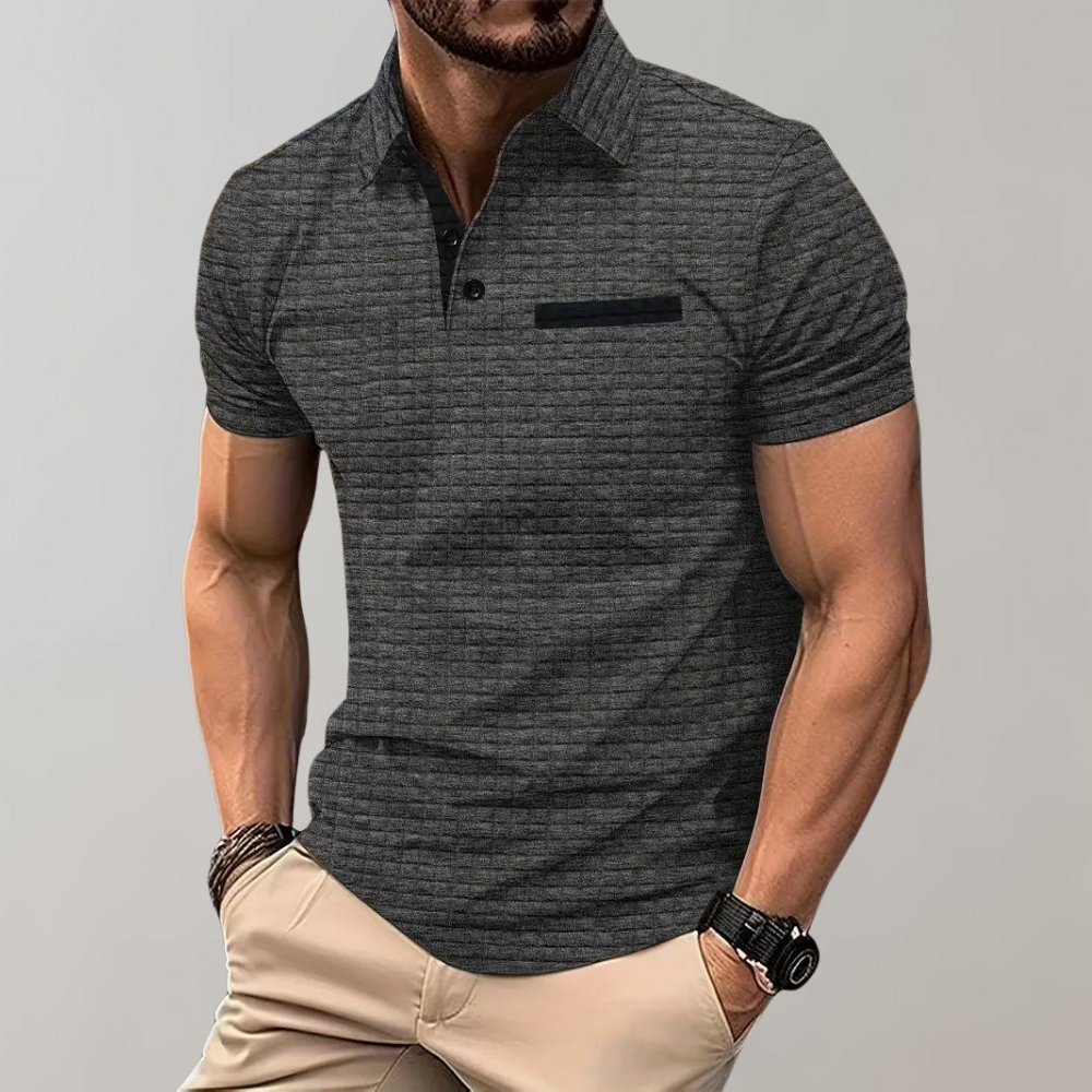 Homme portant un polo gris texturé, manches courtes, avec pantalon beige. Style décontracté, montre noire, mode masculine élégante.