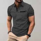Homme portant un polo gris texturé, manches courtes, avec pantalon beige. Style décontracté, montre noire, mode masculine élégante.