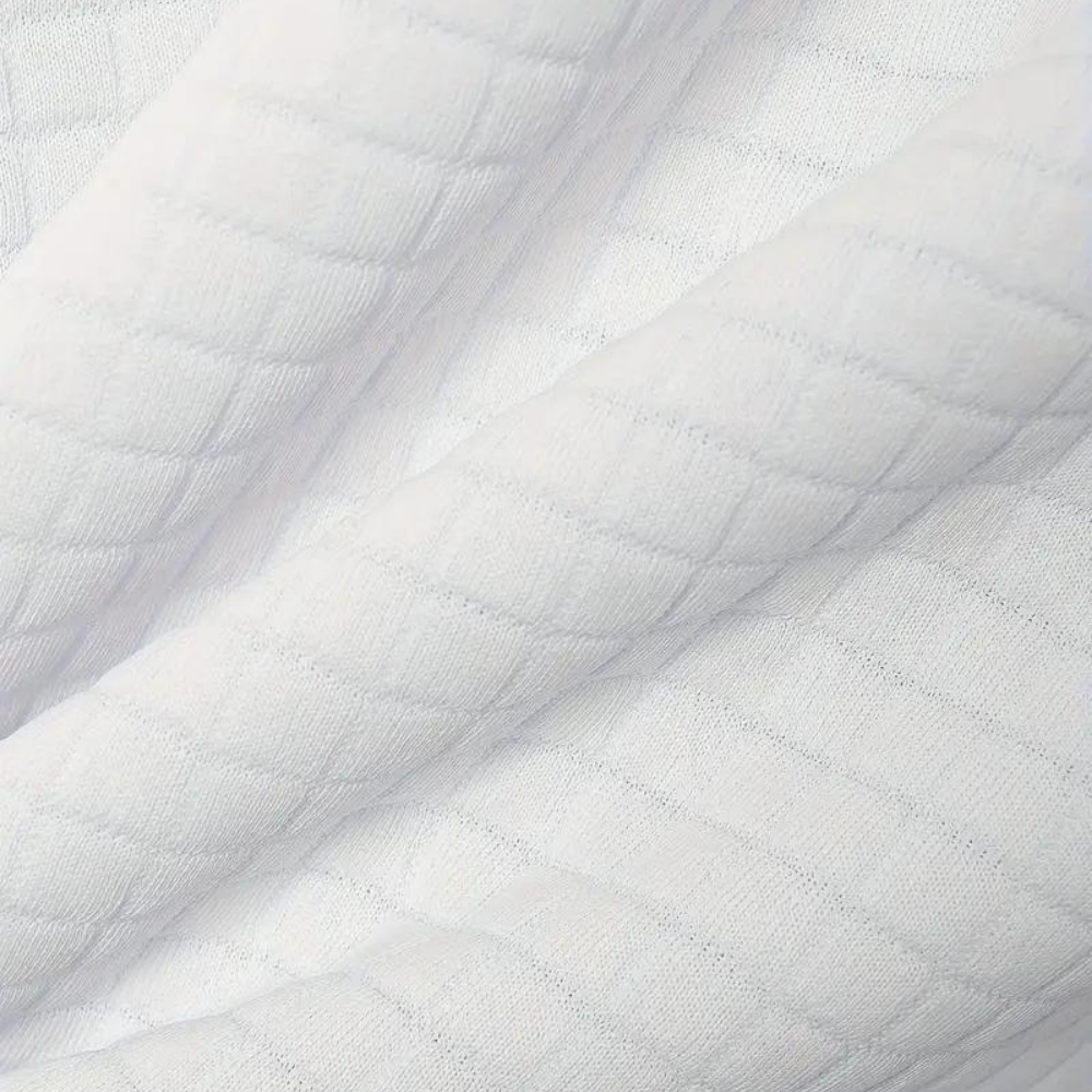Texture de tissu matelassé blanc, doux et confortable, idéal pour la literie ou les vêtements. Motif en losanges, tissu de haute qualité.