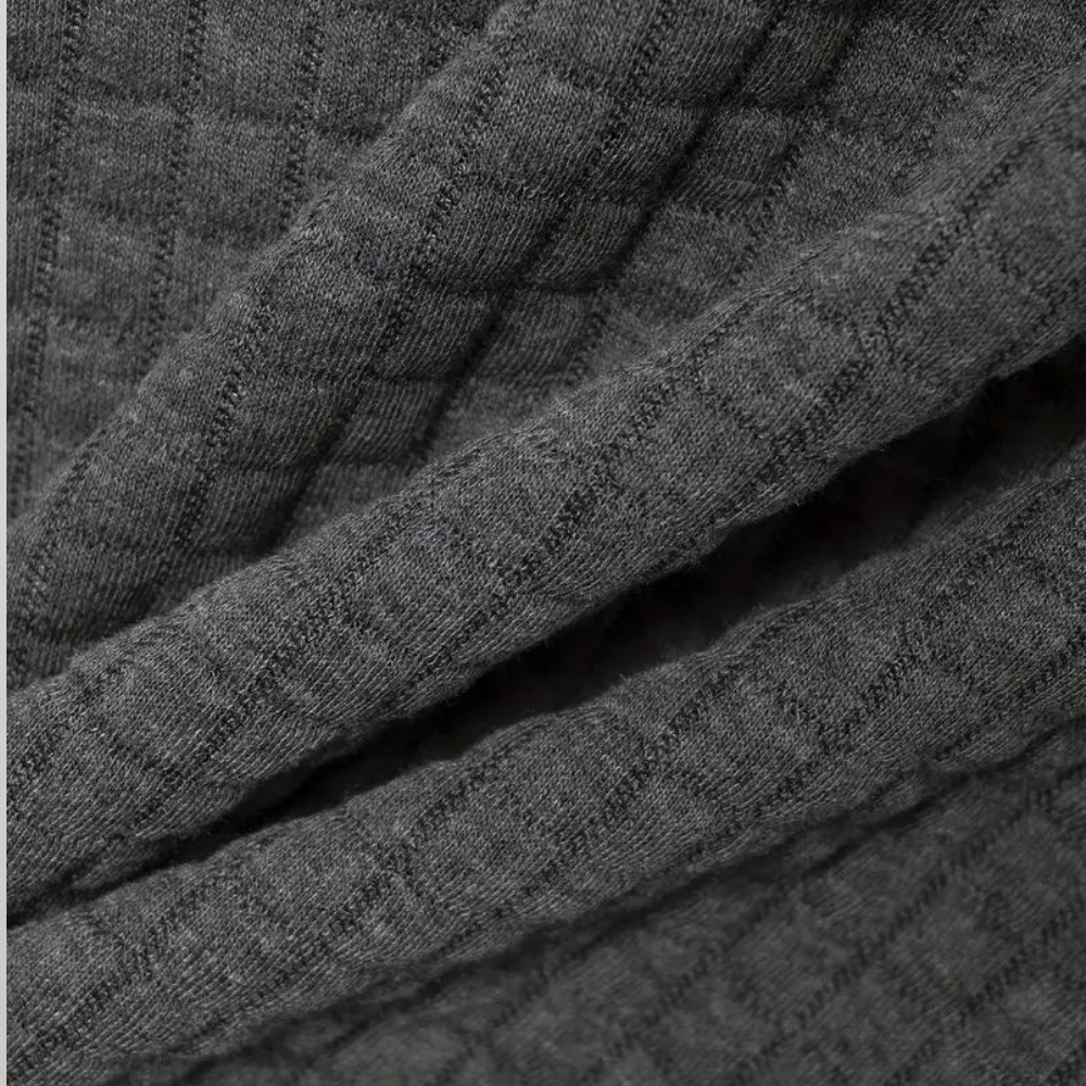 Tissu gris texturé en maille côtelée, motif quadrillé. Textile doux et épais, idéal pour vêtements d'hiver. Mode, confort, chaleur.