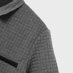 Veste en laine grise à motif quadrillé, col classique, poche poitrine noire, style élégant et moderne, mode automne-hiver.