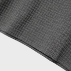 Tissu gris texturé en coton gaufré, motif à carreaux, fond blanc. Textile doux et élégant pour vêtements, décoration intérieure, couture.