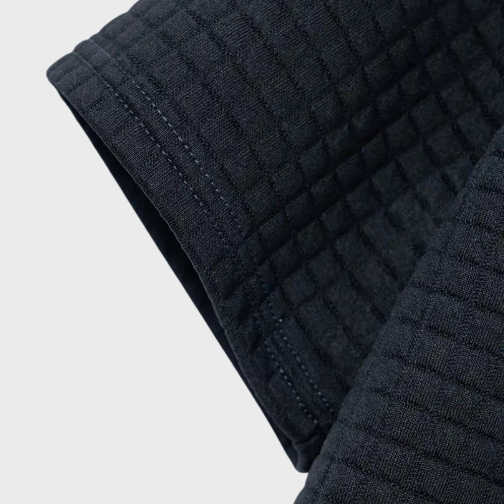 Manche de kimono noir en tissu gaufré, texture quadrillée, couture visible. Vêtement d'arts martiaux, judo, karaté, uniforme traditionnel.