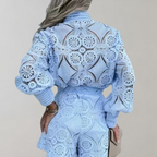 Combinaison en dentelle bleue avec motifs circulaires, manches longues bouffantes, tenue élégante et moderne, mode féminine tendance.