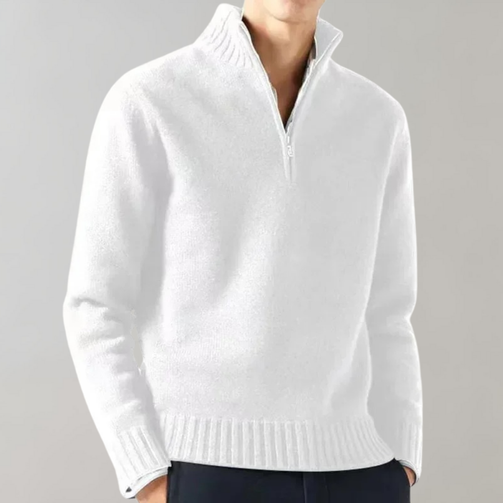 Homme portant un pull blanc à col zippé, manches longues, sur fond gris. Mode masculine élégante, tenue d'hiver confortable et moderne.