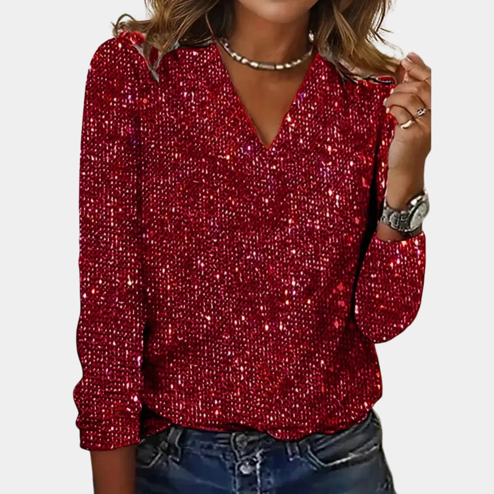 Femme portant un haut à paillettes rouges, manches longues, col en V, avec un collier et une montre, style chic et moderne.