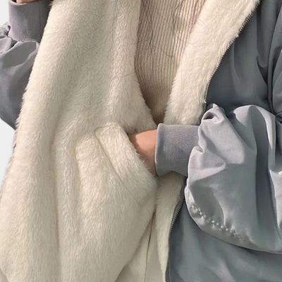 Veste en fausse fourrure blanche et tissu gris, style hiver, avec main dans la poche. Mode tendance, confort et chaleur pour la saison froide.