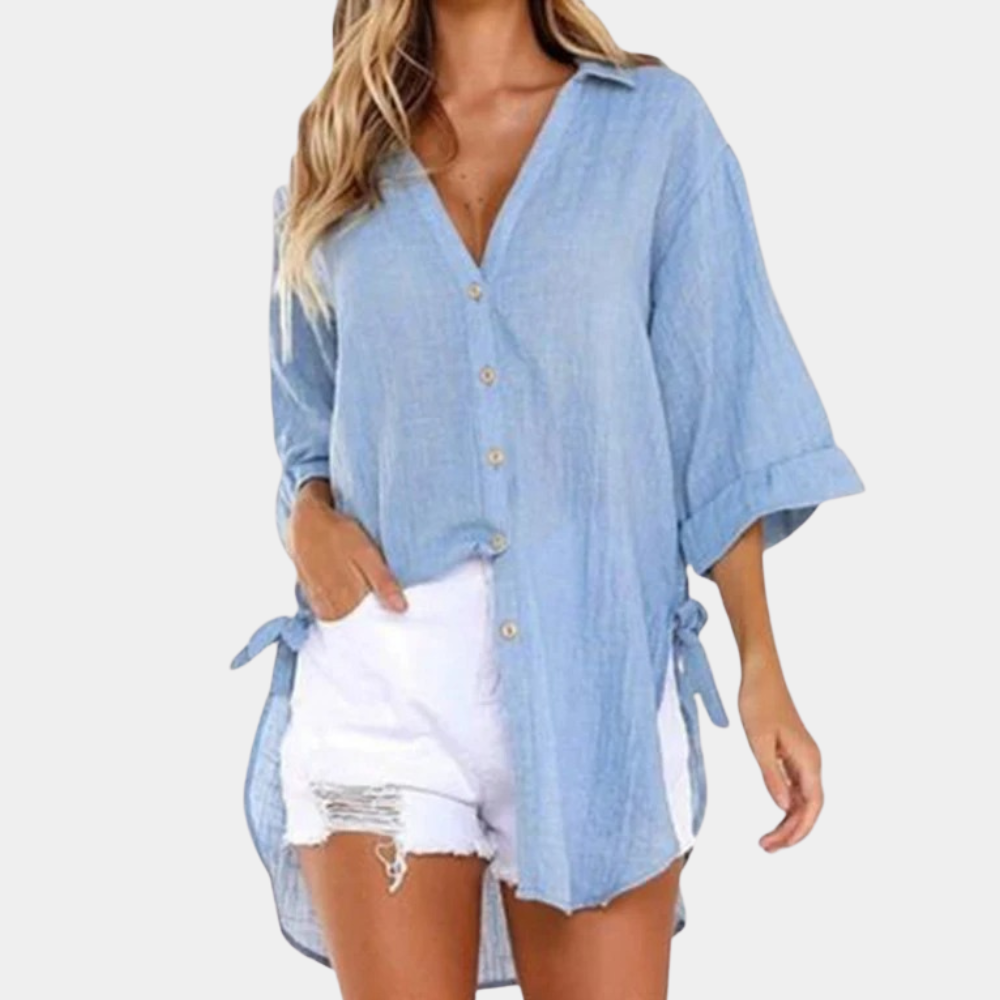 Femme portant une chemise en jean bleu clair avec manches retroussées et short blanc déchiré. Mode décontractée, tendance estivale, style urbain.