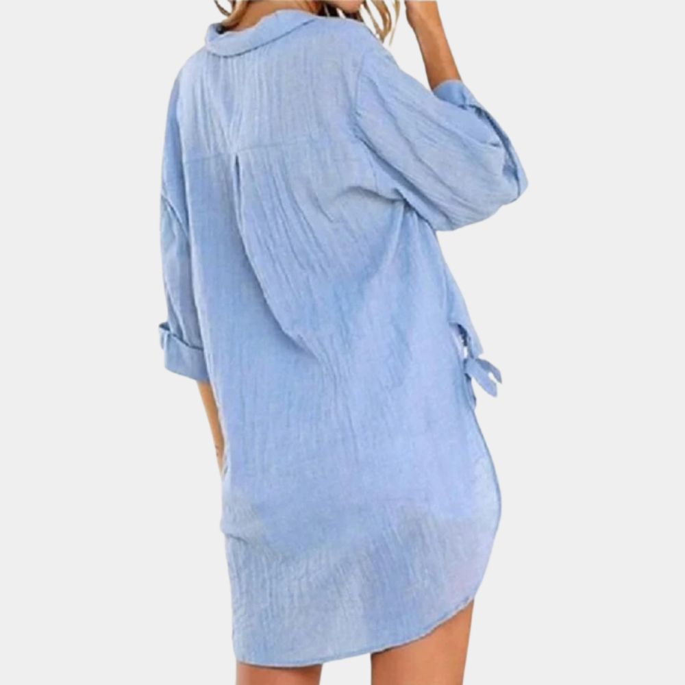 Robe chemise bleue en lin pour femme, manches longues retroussées, style décontracté, vue de dos, idéale pour l'été et la plage.