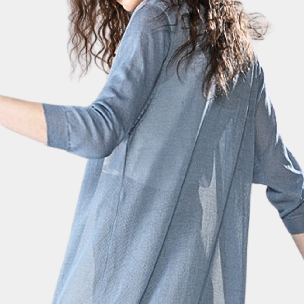 Femme portant une chemise en jean bleu clair, manches trois-quarts, cheveux bouclés. Mode décontractée, style moderne, tendance féminine.