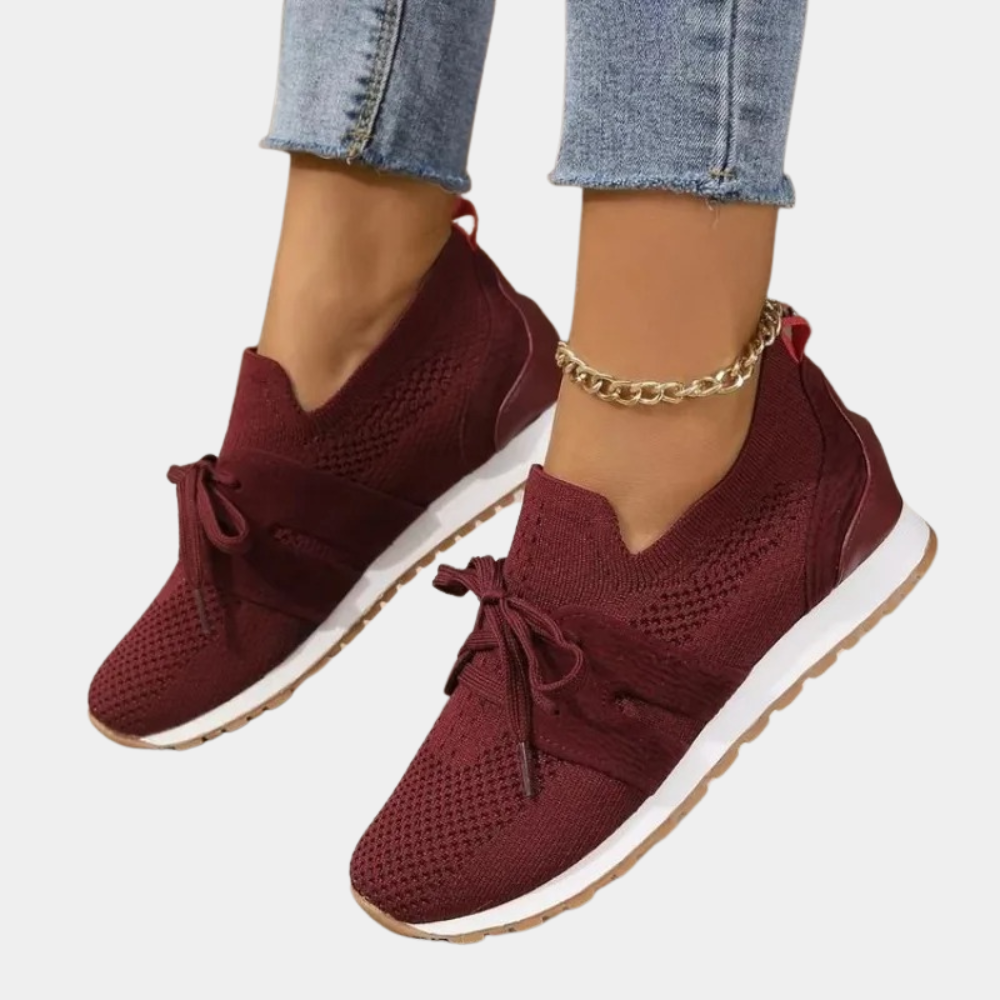 Baskets rouges en maille respirante avec lacets, portées avec un jean bleu. Chaussures de sport tendance pour femme, confortables et élégantes.