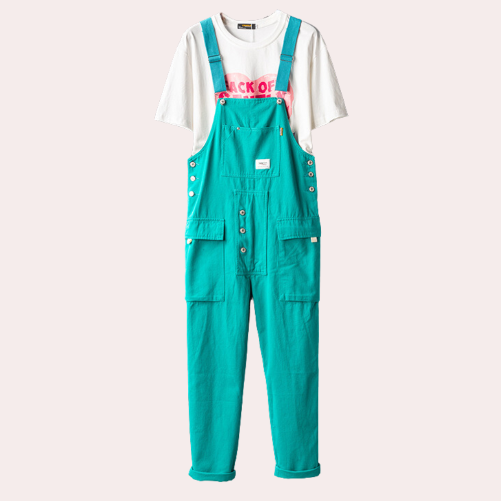 Salopette turquoise en coton avec boutons argentés, poches avant, portée sur un t-shirt blanc imprimé rose. Mode décontractée, tendance et colorée.