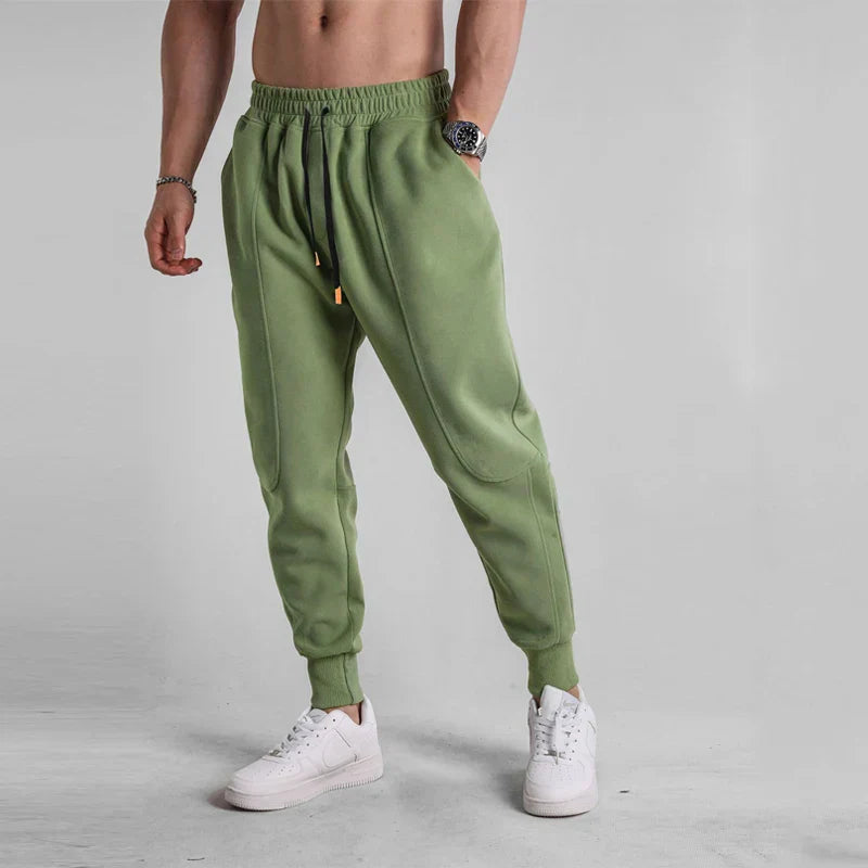 Pantalon de jogging vert pour homme, style décontracté, avec cordon de serrage, porté avec des baskets blanches. Mode masculine tendance.