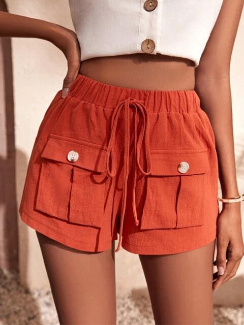 Short en lin orange avec poches à boutons, taille élastique et cordon, porté par une femme. Mode estivale, tenue décontractée, style tendance.