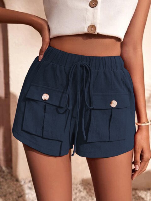 Femme portant un short bleu marine avec poches à boutons et cordon, haut blanc sans manches, style estival décontracté, mode féminine tendance.