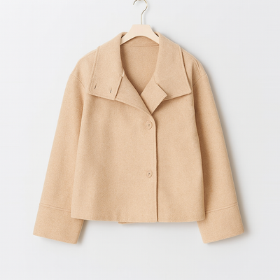Veste beige en laine pour femme, style élégant et moderne, avec col large et boutons, suspendue sur un cintre. Mode automne-hiver tendance.