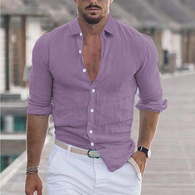 Homme en chemise violette décontractée, manches retroussées, marchant sur un ponton en bois, style estival élégant, mode masculine tendance.