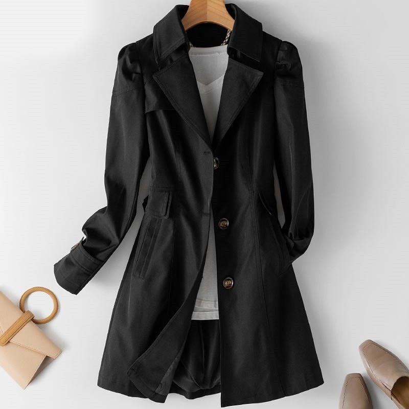 Manteau noir élégant pour femme sur cintre, avec col à revers et boutons, accompagné d'un sac beige et de chaussures à talons. Mode automne chic.