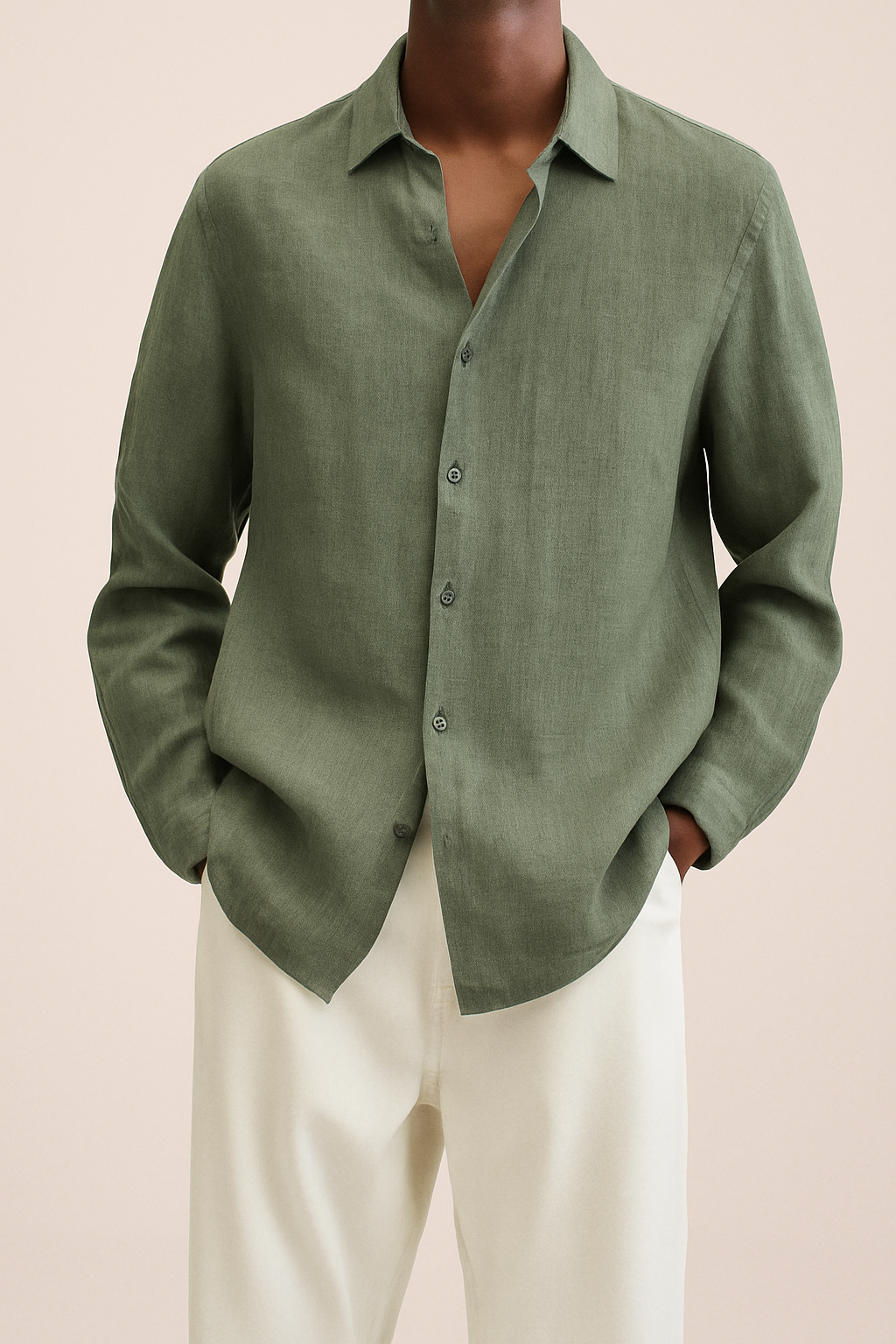 Chemise verte en lin pour homme, manches longues, col classique, portée avec un pantalon blanc. Mode masculine élégante et décontractée.