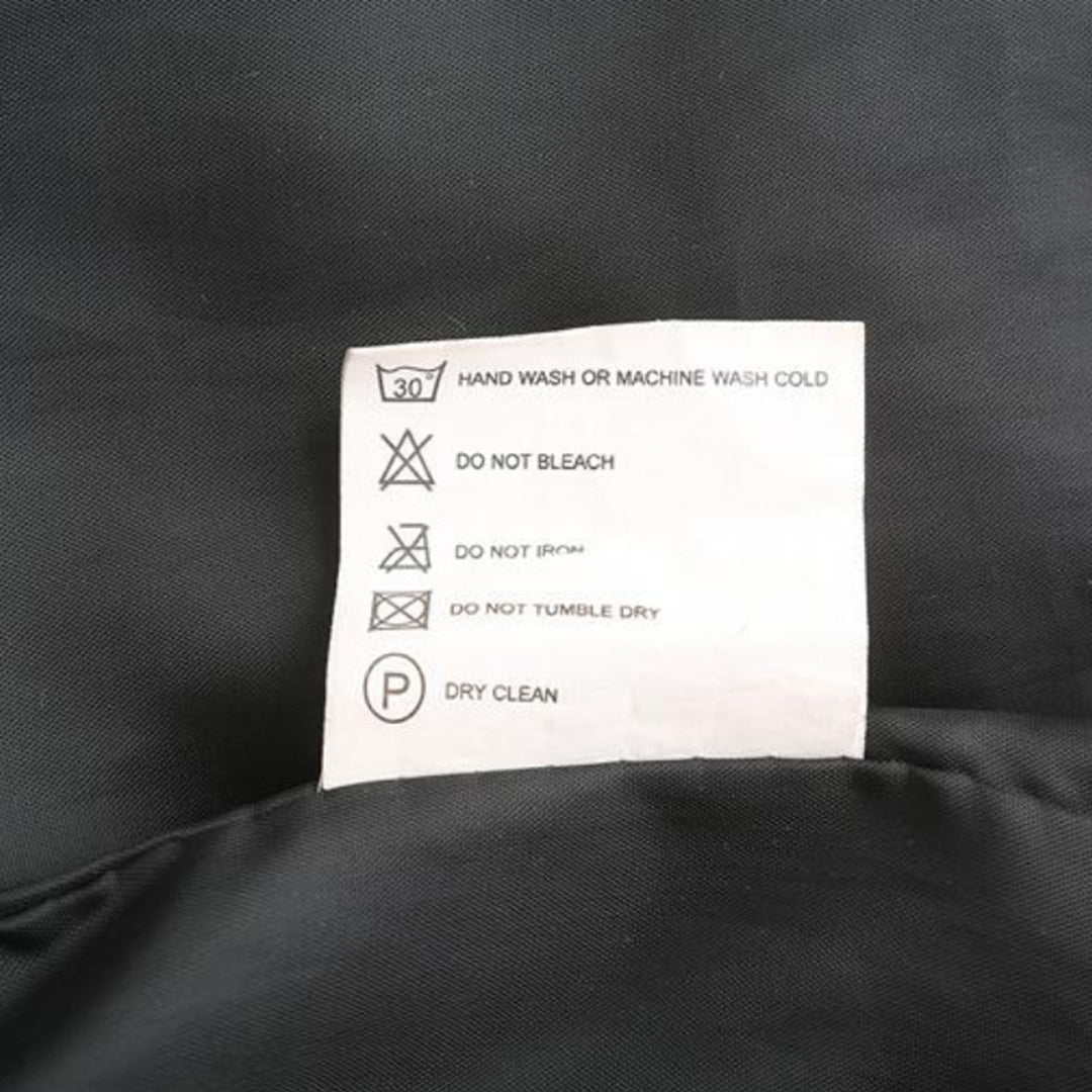 Étiquette d'entretien textile sur tissu noir, indiquant lavage à la main ou machine à froid, ne pas blanchir, repasser, sécher en machine, nettoyage à sec.