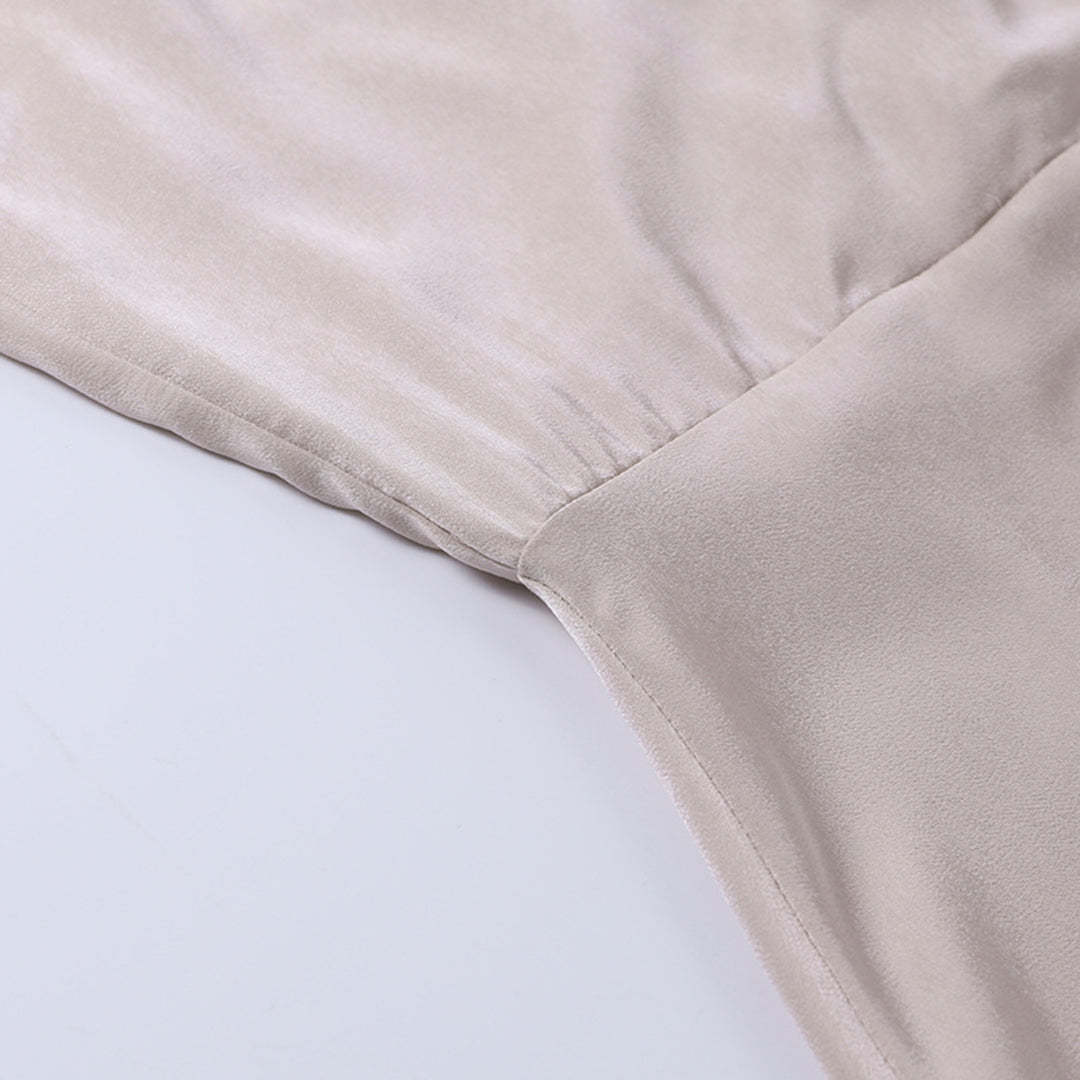 Robe en satin beige, tissu doux et brillant, couture élégante, mode féminine, vêtement chic, détail de texture luxueuse.