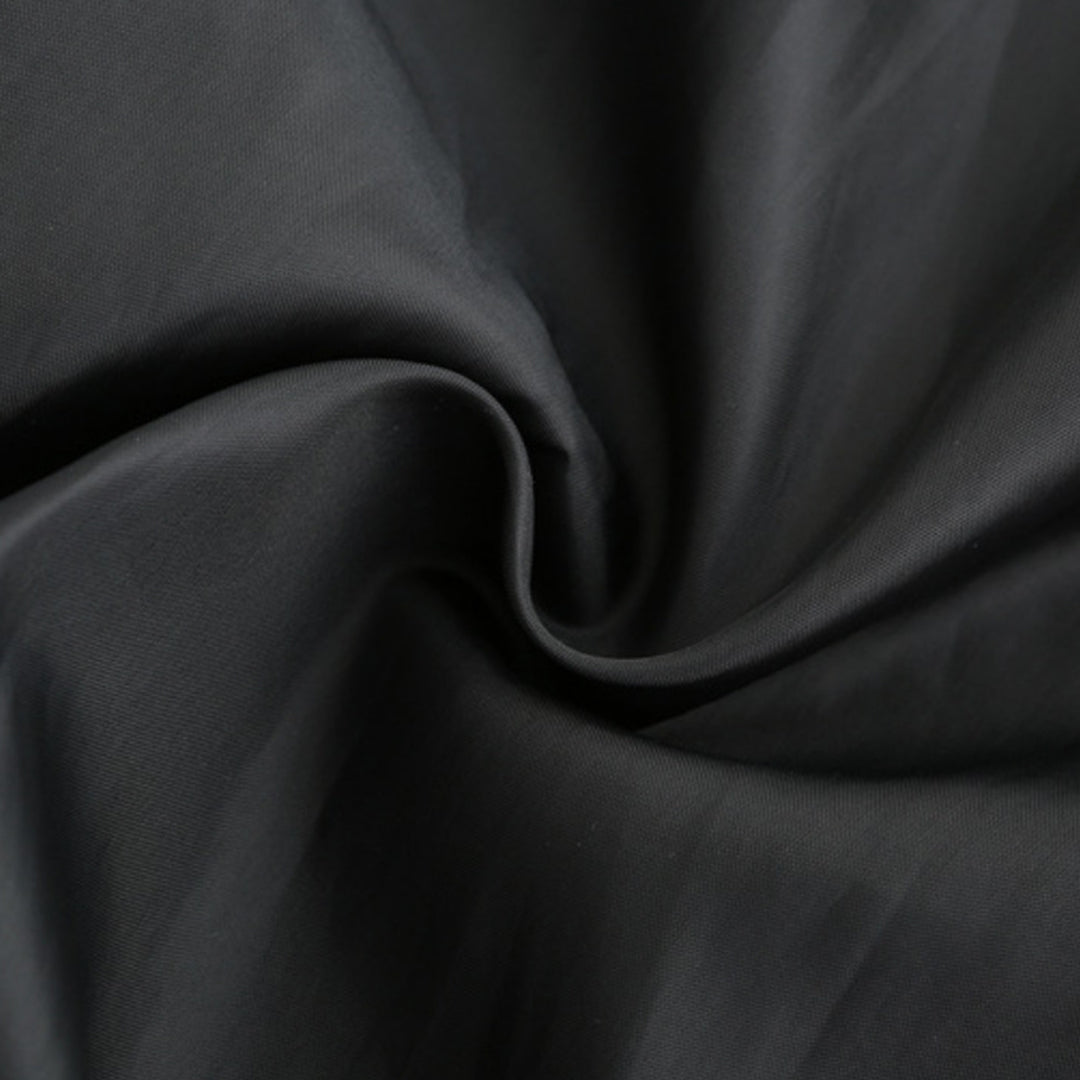 Tissu noir en coton, texture douce et lisse, idéal pour couture et mode. Matériau de haute qualité, parfait pour vêtements et décoration.