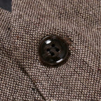 Bouton noir sur veste en tweed marron texturé, gros plan. Mode masculine élégante, détail couture, tissu automne-hiver, style classique.