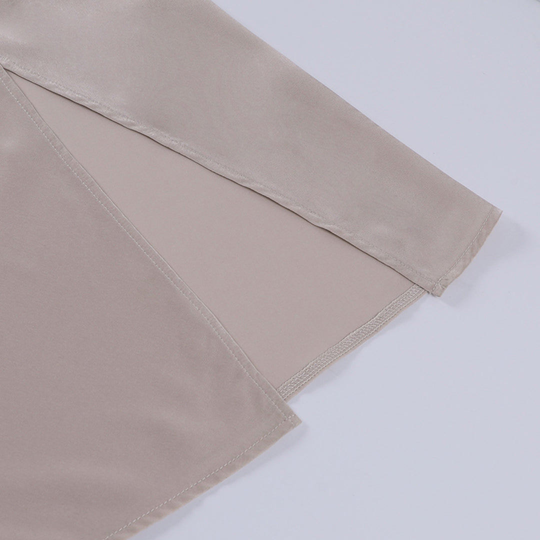 Manche de chemisier en satin beige, tissu lisse et brillant, couture fine, mode élégante, vêtement féminin chic, détail textile luxueux.