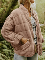 Femme portant une veste matelassée rose, manches longues, avec fermeture éclair, dans un cadre naturel. Mode automne, style décontracté, tendance.