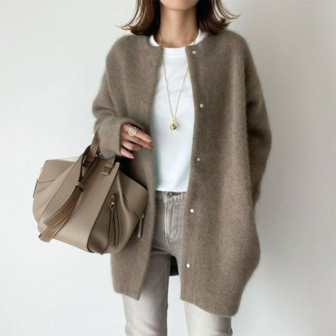 Femme portant un manteau en laine marron, t-shirt blanc, jean beige, sac à main taupe, collier doré. Mode automne chic et décontractée.