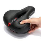 Selle de vélo ergonomique noire avec zone de ventilation, design antidérapant, main appuyant pour montrer le confort et la souplesse.