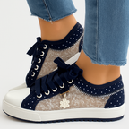 Baskets en dentelle transparente avec détails floraux, lacets noirs et semelle blanche, portées avec un jean bleu. Mode féminine, chaussures tendance.