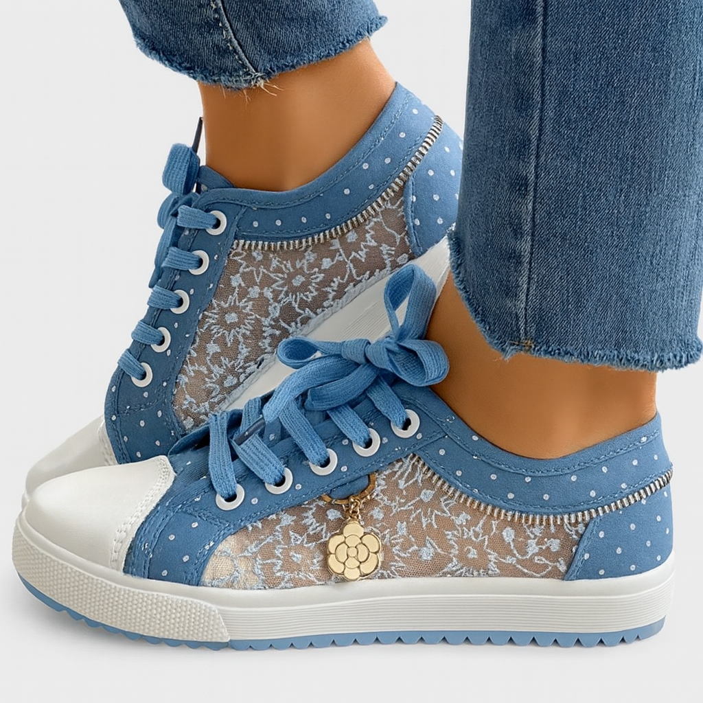 Baskets en dentelle bleue pour femme avec lacets, motif floral, semelle blanche et pendentif fleur, portées avec un jean. Mode féminine tendance.