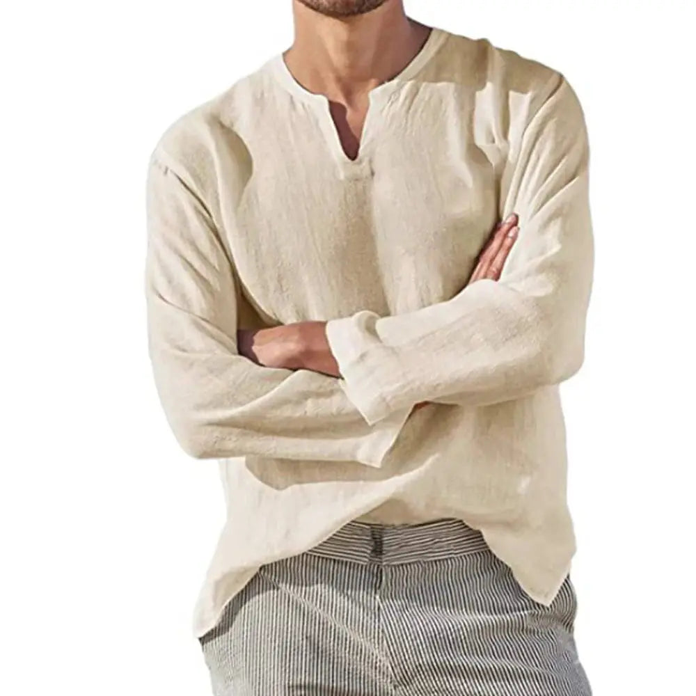 Homme portant une chemise en lin beige à col en V, manches longues, associée à un pantalon rayé. Mode décontractée, style estival élégant.