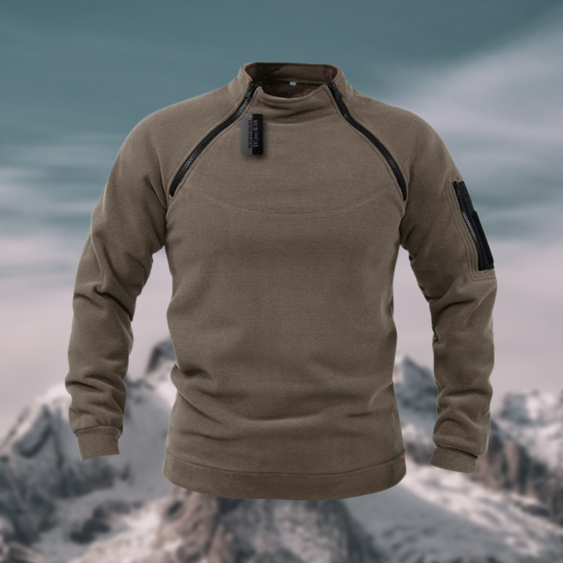 Sweat-shirt marron pour homme avec fermeture éclair, poche sur la manche, devant un paysage montagneux enneigé. Mode outdoor, vêtement chaud.