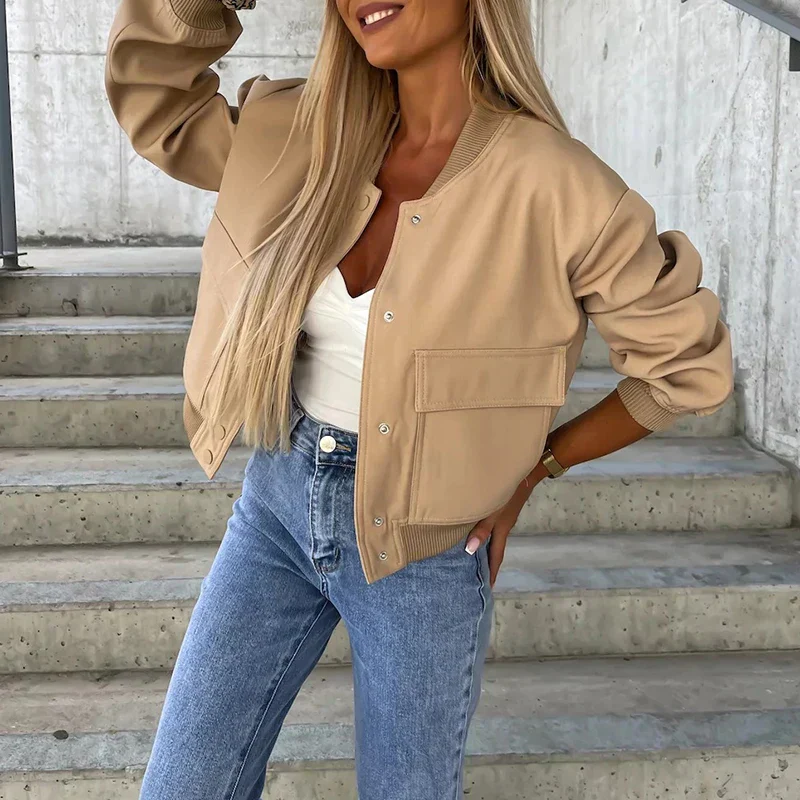 Femme portant un blouson beige tendance, t-shirt blanc et jean bleu, posant sur des escaliers en béton. Mode automne, style décontracté chic.