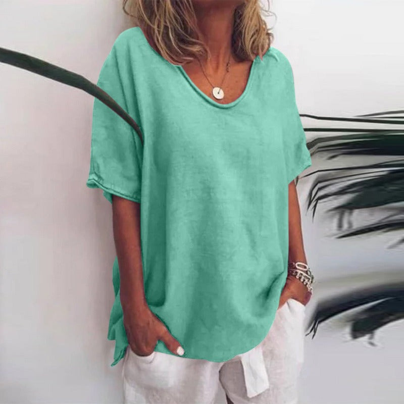 Femme portant un t-shirt vert menthe ample, col rond, manches courtes, avec un pantalon blanc. Mode décontractée estivale, style tendance.