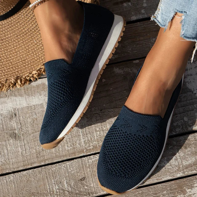 Chaussures en maille bleu marine pour femme sur plancher en bois, style décontracté, confortables, idéales pour l'été, avec semelle blanche antidérapante.