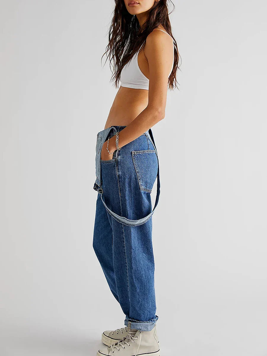 Femme en jean baggy bleu et brassière blanche, posant de profil. Mode décontractée, tendance streetwear, chaussures blanches montantes.