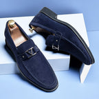 Chaussures mocassins en daim bleu marine pour homme, élégantes et modernes, posées sur fond bleu. Accessoire mode masculin tendance.