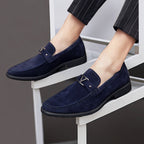 Chaussures mocassins en daim bleu marine pour homme, élégantes et modernes, portées avec un pantalon à rayures. Mode masculine, style chic.