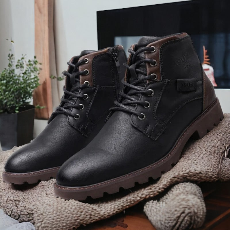 Bottes en cuir noir pour homme avec lacets, semelle robuste, posées sur un tapis beige, plante verte en arrière-plan. Chaussures élégantes et durables.