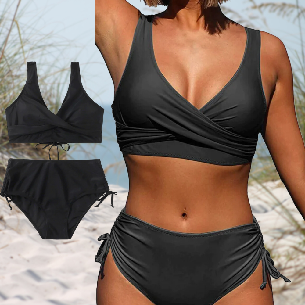 Femme en bikini noir à taille haute sur plage, maillot de bain deux pièces élégant, style croisé, idéal pour l'été et les vacances à la mer.
