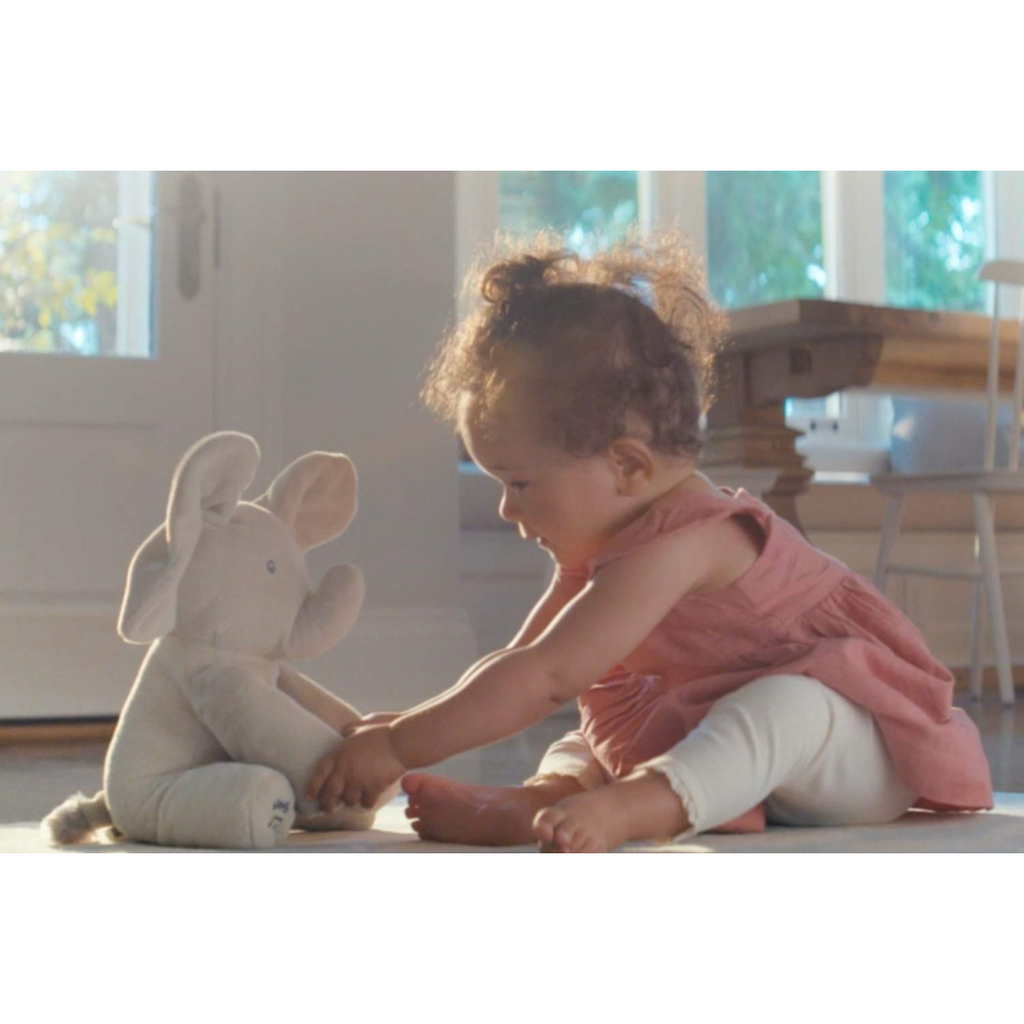 Enfant jouant avec une peluche éléphant dans un salon lumineux; jouet doux, bébé heureux, intérieur moderne, moment de tendresse.
