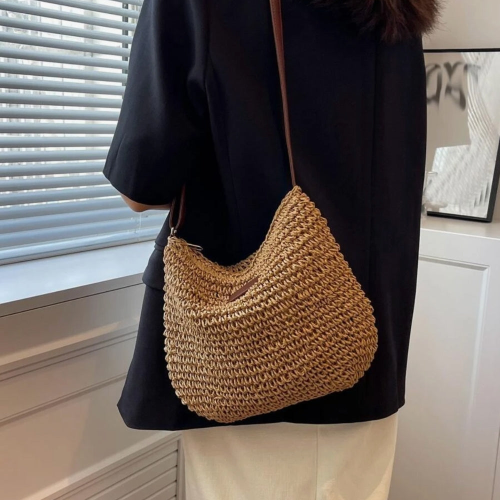 Sac à bandoulière en paille tressée porté par une personne, style décontracté, idéal pour l'été. Accessoire mode tendance, parfait pour la plage.