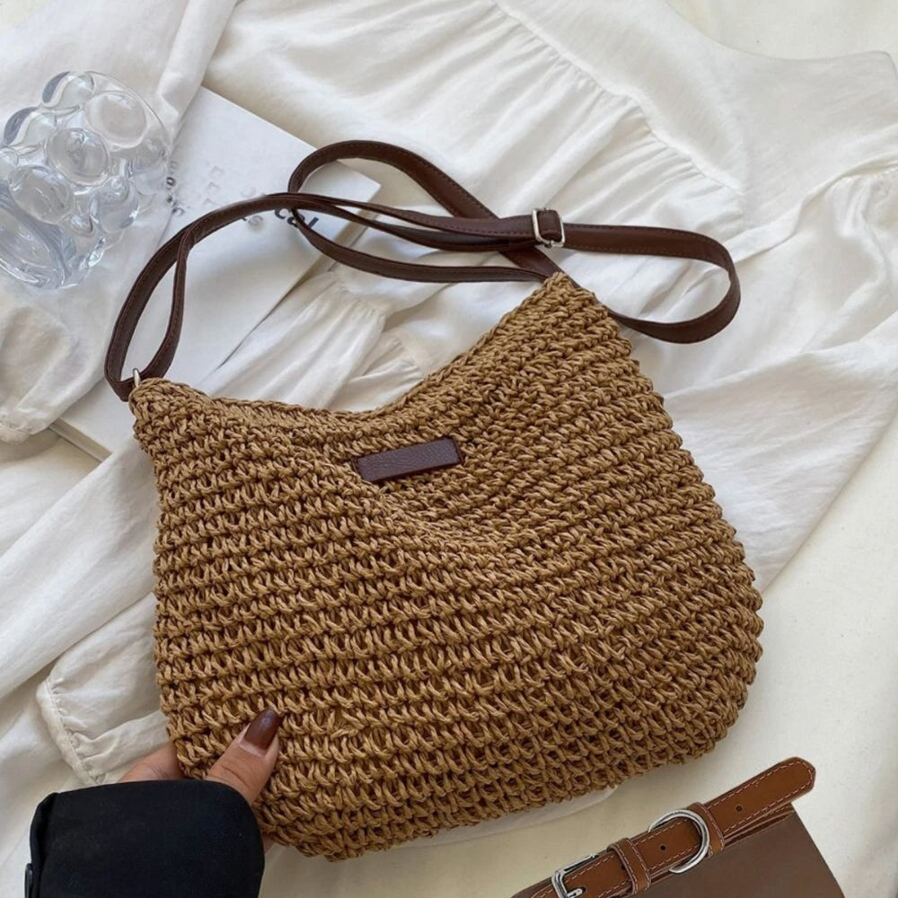 Sac à main en paille tressée marron avec bandoulière en cuir, posé sur une robe blanche. Accessoire mode tendance, idéal pour l'été.
