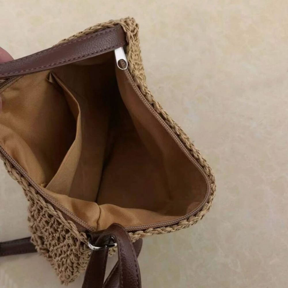 Sac à main en paille tressée avec doublure beige, bandoulière en cuir marron, ouvert pour montrer l'intérieur spacieux. Accessoire mode tendance.