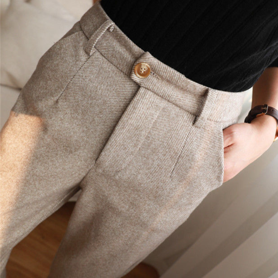 Pantalon en laine beige pour femme, coupe droite, avec bouton en bois, porté avec un pull noir. Mode élégante et confortable pour l'hiver.