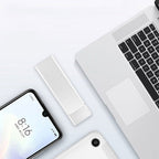 Clé USB blanche posée sur un bureau avec un ordinateur portable argenté et un smartphone moderne, technologie de stockage portable élégante.