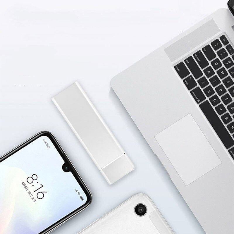 Clé USB blanche posée sur un bureau avec un ordinateur portable argenté et un smartphone moderne, technologie de stockage portable élégante.